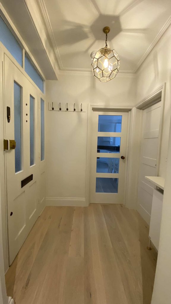 Hallway renovation South London by LMDEC LTD Elegant entrance hallway with geometric chandelier and blue glass doors Kensington flat refurbishment