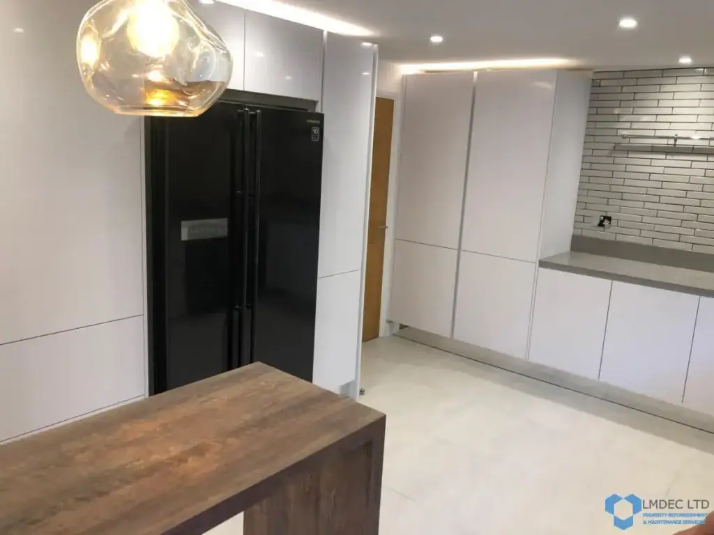 Expansive Croydon kitchen diner with white cabinets flowing to wooden breakfast bar, double oven range cooker, gray composite worktop, large garden window, and porcelain tile floors