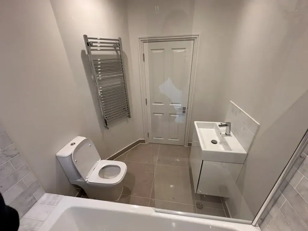 Close-up of glossy white floating vanity cabinet with rectangular basin, chrome single-lever mixer tap, and soft-close drawer in a renovated Balham home bathroom.