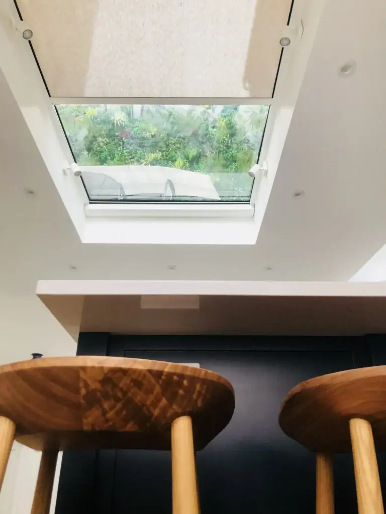 Overhead view of fabric-lined roof lantern with recessed spotlights, white ceiling panels, and exposed beams in a renovated Kensington luxury kitchen