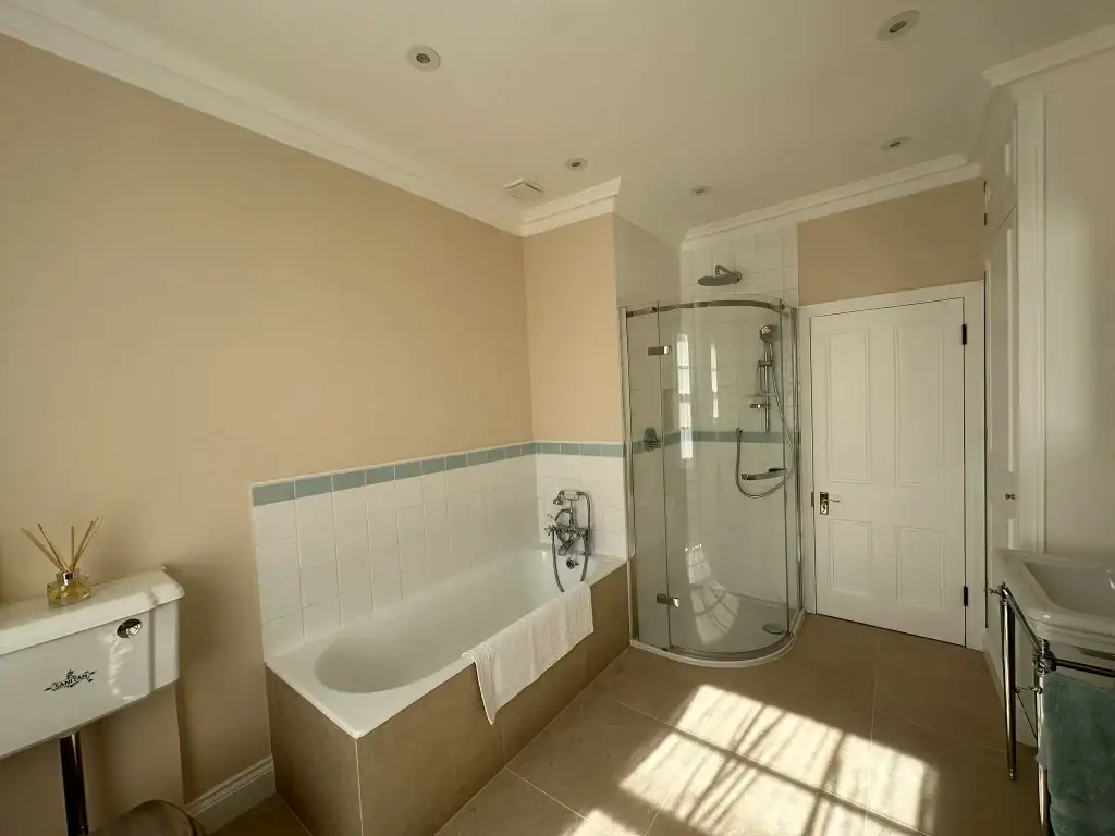 Traditional inset bath and curved glass shower beneath original coving in Pimlico