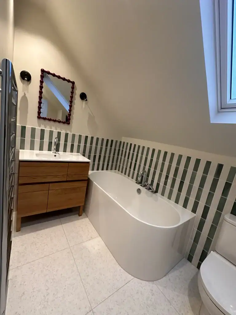 Feature wall of large-format porcelain tiles with Polished chrome towel rails and underfloor heating in a renovated Wimbledon bathroom
