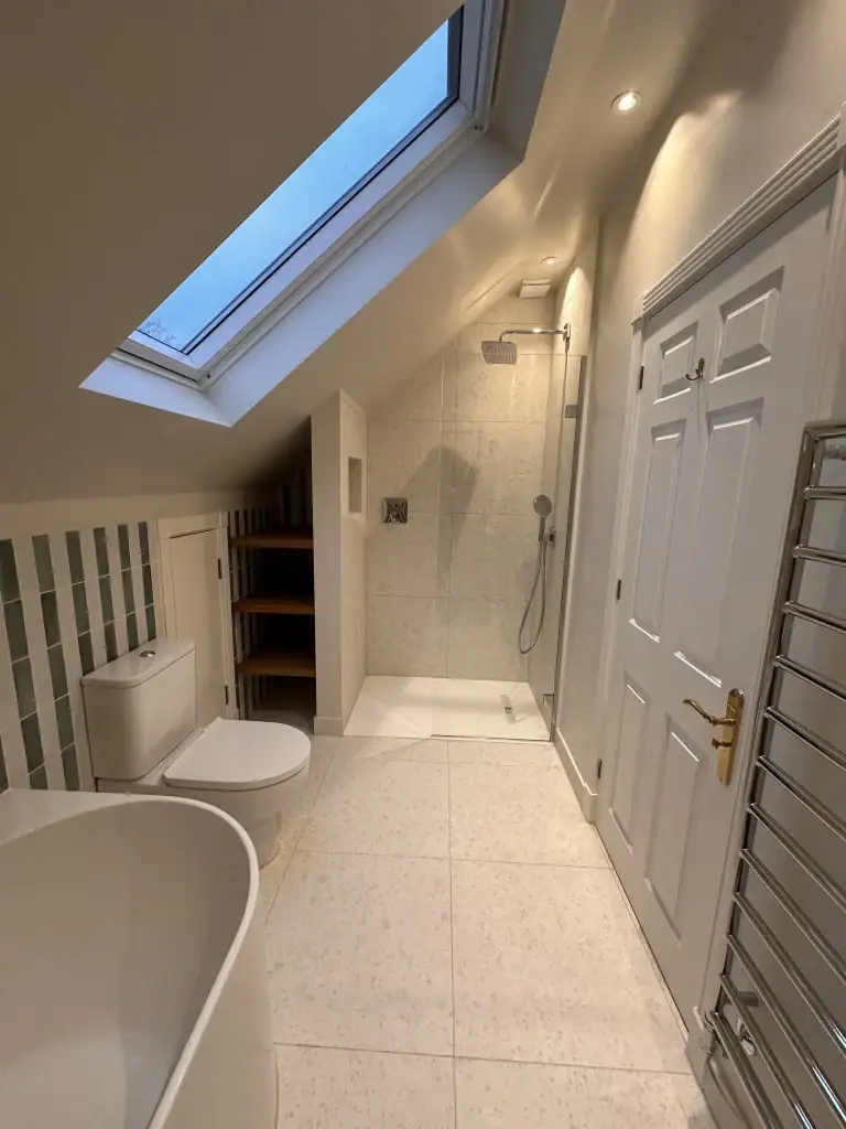 Spacious contemporary white bathroom with freestanding tub, rainfall shower, and marble vanities in a Wimbledon home renovation project.