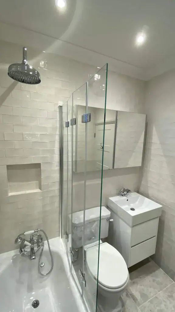 Chrome rainfall shower and heated towel radiator against white metro tiles in South Kensington