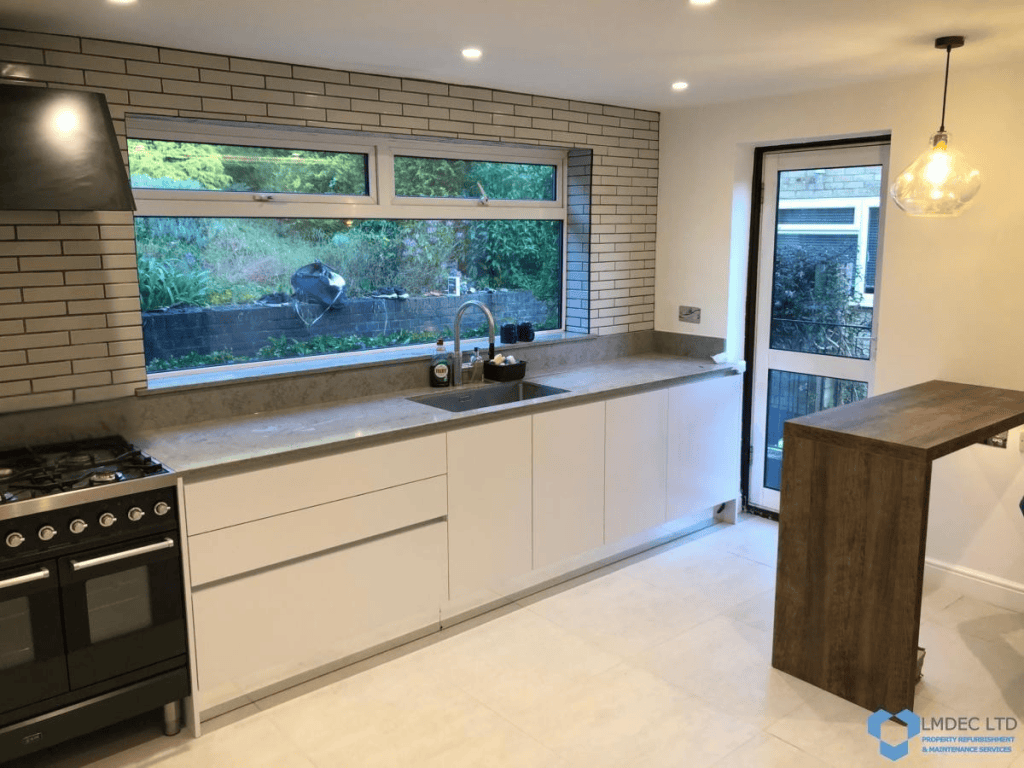 Contemporary Croydon kitchen run with matte charcoal granite counters, five-burner gas hob, stainless undermount sink, white glossy base cabinets, brick-effect splashback, and garden window view